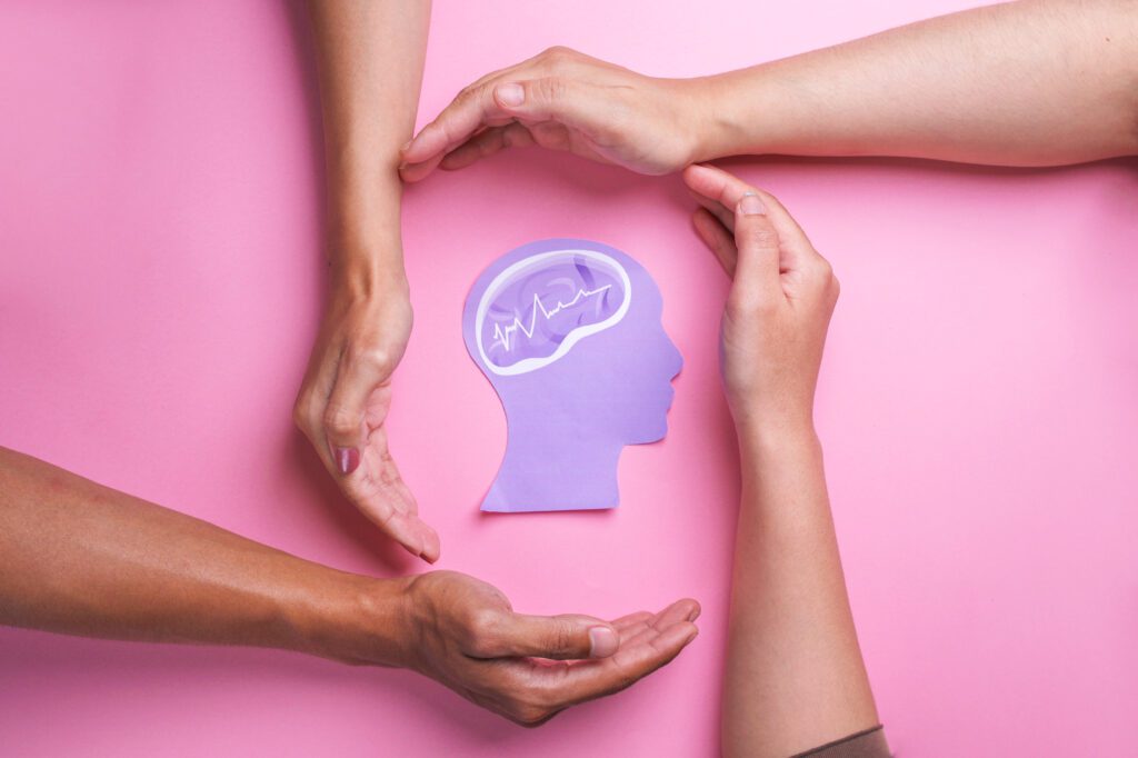 hands surrounding a paper image of a human brain symbolizing mental wellness vs mental illness