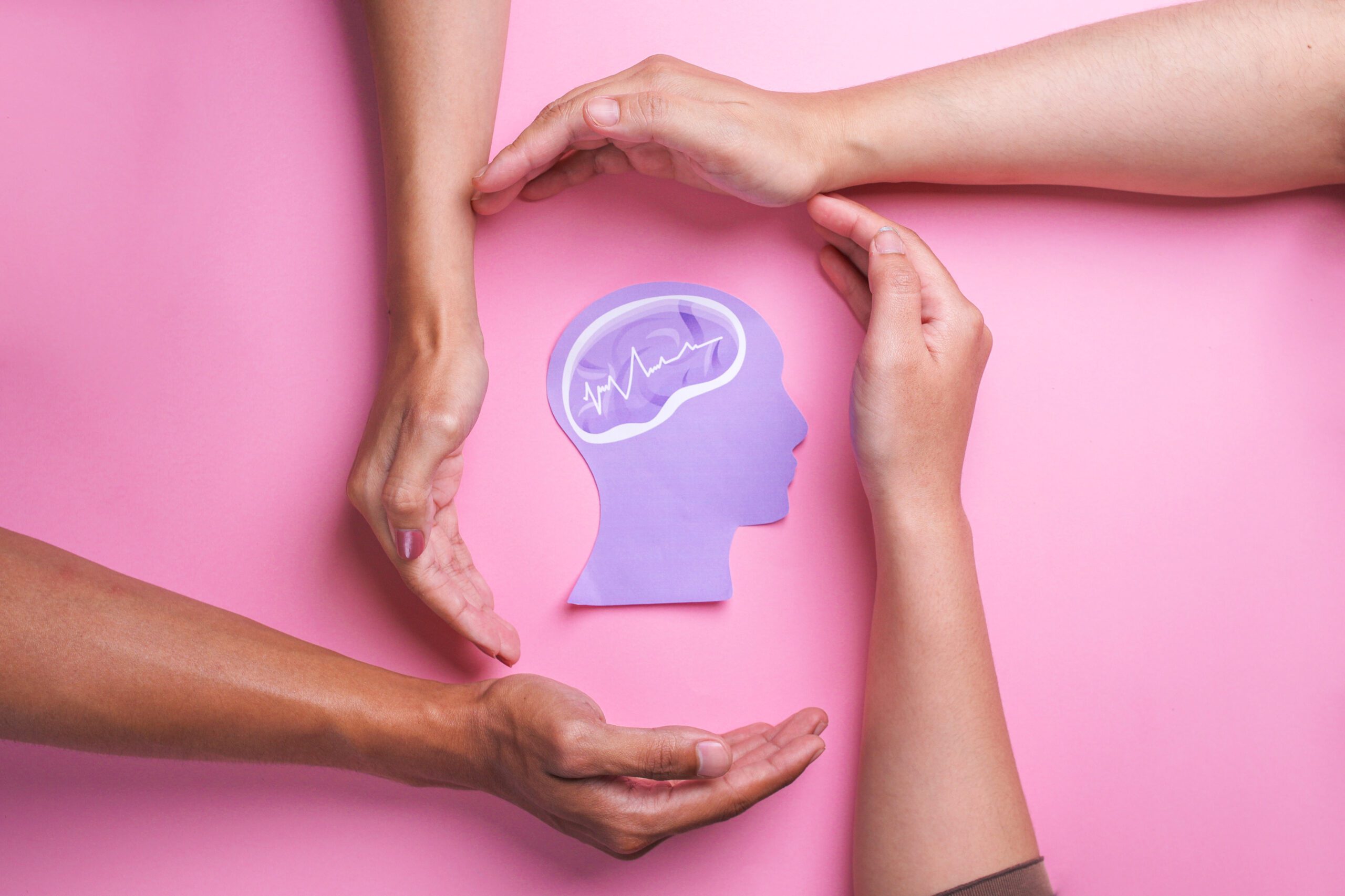 hands surrounding a paper image of a human brain symbolizing mental wellness vs mental illness