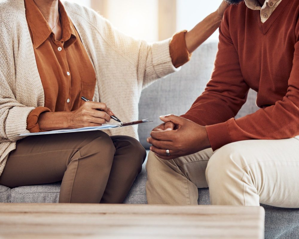 Therapy, counseling and grief with a black man patient and woman counselor talking in session. Writ